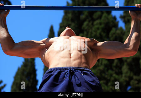 Primo piano della giovane forte atleta adolescente facendo pull-up sulla barra orizzontale Foto Stock