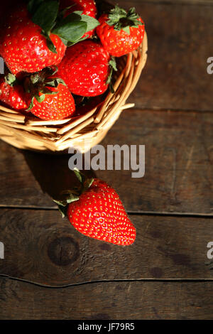 Ancora in vita con freschezza fragola rossa nel cesto di vimini sulla vecchia superficie in legno Foto Stock