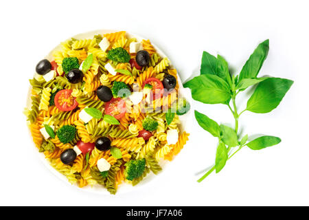 Piatto di insalata di pasta con foglie di basilico su bianco Foto Stock