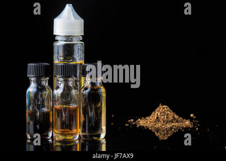 E-liquido bottiglie accanto al macinato di foglie di tabacco e la nuvola di fumo Foto Stock