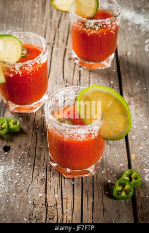 Messicano alcool tradizionale bevanda. Sangrita, con tequila, succo di pomodoro, hot spezie, peperoncino e calce.analoga bloody mary. Su tavola in legno rustico, cop Foto Stock