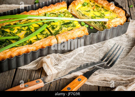 Francese home la cucina. Casseruola. Torta. Quiche Lorraine da pasta sfoglia, con giovani di cipollotti e spinaci. Sul vecchio rustico in legno tavolo. Tagliare. Nella forma f Foto Stock