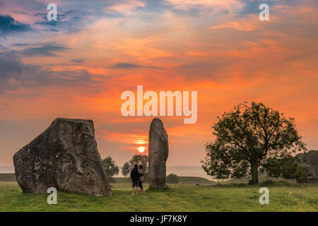 Le nuvole parte come Aurora rompe su antiche pietre Sarsen ad Avebury nel Wiltshire il giorno prima del solstizio d'estate. Foto Stock