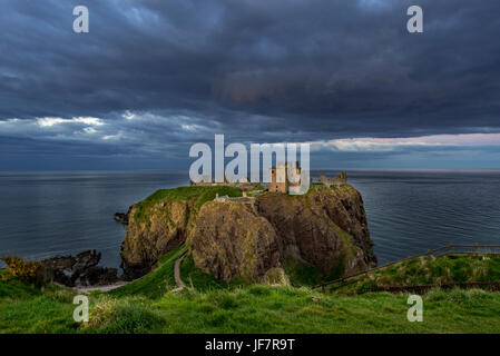 Minacciose nuvole scure sopra il castello di Dunnottar, rovinato fortezza medievale vicino a Stonehaven a picco sul mare lungo la costa del Mare del Nord, Aberdeenshire, Scozia Foto Stock