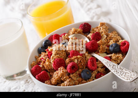 Muesli con lamponi e mirtilli, latte e succo di arancia di close-up su una tavola orizzontale. Foto Stock
