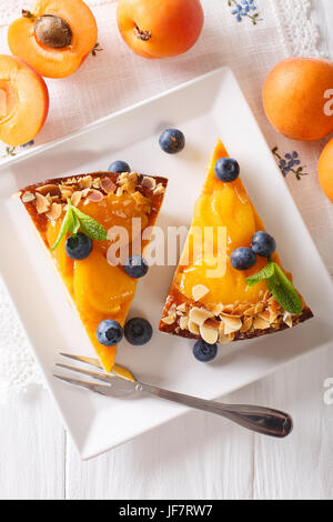 Torta di albicocche con mirtilli e dadi close-up su una piastra. vista verticale da sopra Foto Stock