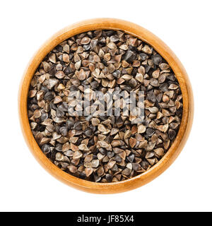 Comune di semi di grano saraceno con scafi in ciotola di legno. Fagopyrum esculentum, anche il giapponese o silverhull grano saraceno. Senza glutine pseudocereal. I semi secchi. Foto Stock