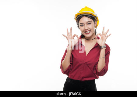 Donna asiatica ingegnere in maglietta rossa e gialla cappuccio di sicurezza rendendo bene l'azione. Persone gesticolando in business e concetto enginerring Foto Stock