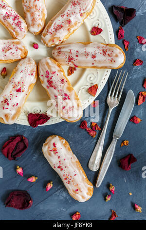 La vaniglia eclairs con petali di rosa. Foto Stock