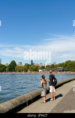 Un uomo e una donna godendo della vista sulla Kitsilano seawall percorso con Kitsilano Beach e English Bay nel retro, Vancouver, British Columbia, Canada Foto Stock