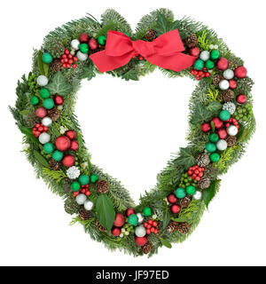 Natale a forma di cuore decorazione ghirlanda con fiocco rosso, baubles, agrifoglio, vischio e inverno verde su sfondo bianco. Foto Stock