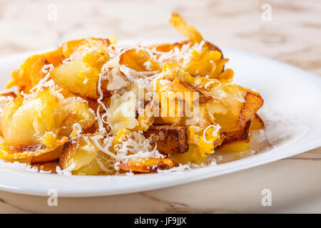 Patate fritte con uova strapazzate e parmigiano sulla piastra bianca Foto Stock