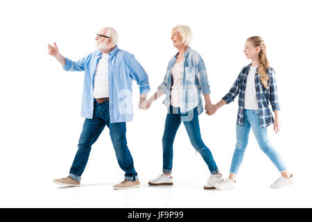 Felice del nonno e la nonna e la nipote a piedi e tenendo le mani insieme isolato su bianco Foto Stock