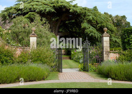 Cancello di ferro aperto alle colorate estate Garden cottage con un grande albero Foto Stock