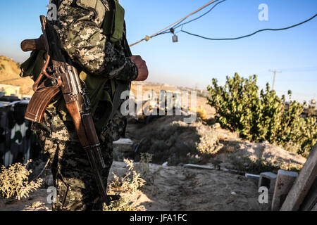 La striscia di Gaza e la striscia di Gaza, Palestina - macchinari palestinese operare sul confine con l'Egitto, a Rafah nella striscia di Gaza il 29 giugno 2017. Forze di sicurezza palestinesi fedeli ad Hamas in stand by come bulldozer cancellare una zona per una grande zona di buffer al confine con l'Egitto nel sud della striscia di Gaza città di Rafah, il 29 giugno 2017. La zona di buffer è previsto che si estendono per una lunghezza di 12 chilometri e con una larghezza di 100 metri lungo il confine con una strada e telecamere di sicurezza in esecuzione in parallelo, secondo una dichiarazione da parte di un ufficiale di sicurezza. (Foto di Nidal Alwaheidi/Pacific Stampa) Foto Stock