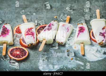 Rosso arancio, yogurt, muesli popsicles su cubetti di ghiaccio, dessert sano Foto Stock