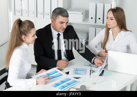 Due giovani belle donne business consulting con il loro collega. Partner documenti di discussione e idee Foto Stock