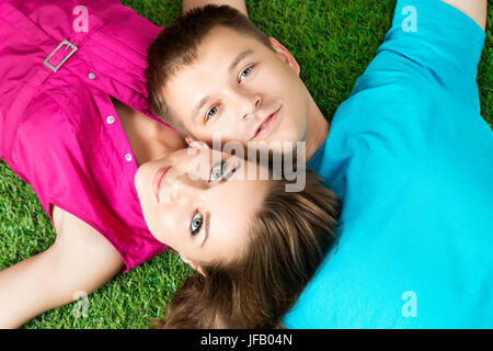 Giovane bella giovane che stabilisce insieme su erba nel parco. Vista dall'alto. Amore e stare insieme concetto. Foto Stock