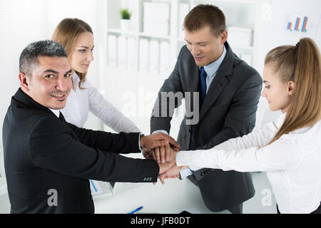 Team aziendale che mostra l'unità di mettere le mani sulla parte superiore di ogni altro. Concetto di lavoro di squadra. Foto Stock