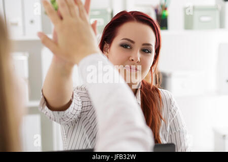 Due donna celebrando qualcosa dando alta cinque presso l'ufficio. Realizzazione di business di successo e finitura del progetto o il concetto di partenariato Foto Stock