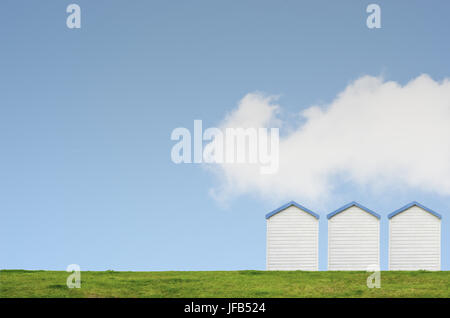 Una fila di tre cabine sulla spiaggia, su di una collina erbosa contro un luminoso cielo blu con un grande bianco soffice nuvola. Copia nello spazio al di sopra e a sinistra. Foto Stock