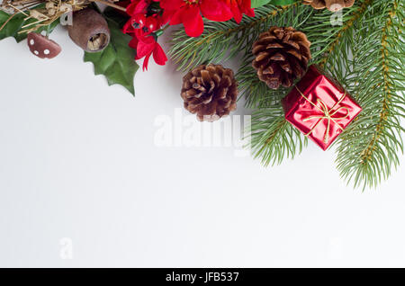 Un Natale a tema in esecuzione di confine dalla parte superiore sinistra alla parte destra del telaio, costituito da una varietà di inverno artificiale flora decorazioni in verdi, rossi a Foto Stock