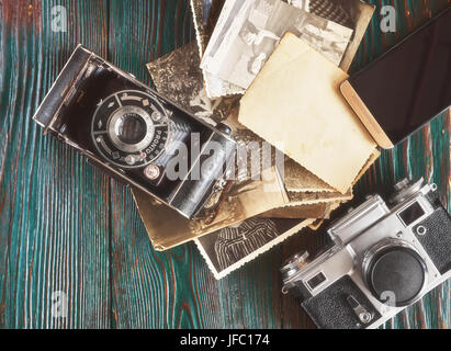 Tre generazioni di macchine fotografiche e vecchie foto sulla memoria. Antico autentico sfondo di legno. Foto Stock