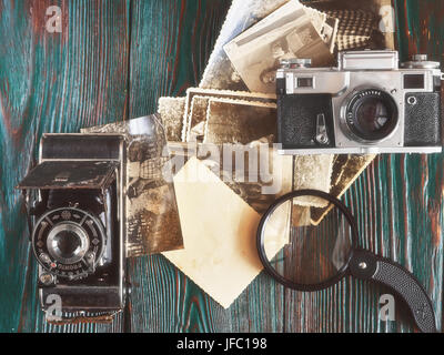 Tre generazioni di macchine fotografiche e vecchie foto sulla memoria. Antico autentico sfondo di legno. Foto Stock