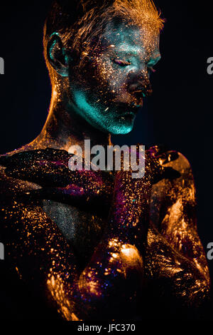 Inquadratura concettuale della luce e la brillantezza dei colori fluorescenti giovani il volto dell'uomo Foto Stock