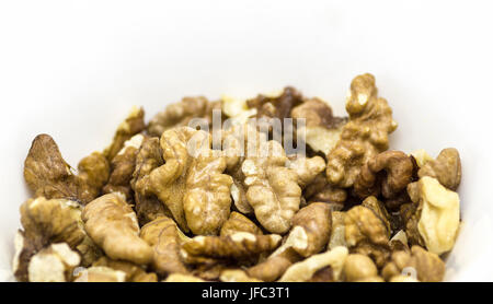 Sbucciate le noci in una tazza closeup su uno sfondo bianco. Foto Stock