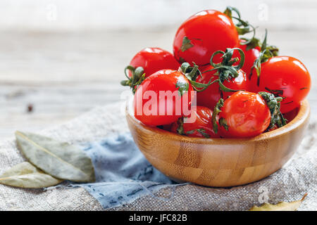 Il salato i pomodori ciliegia in una ciotola di legno. Foto Stock