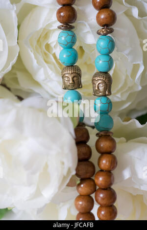 Bellissima perline di legno con pietre preziose chrysocolla, tormalina turchese e fiori su sfondo. Perle di Mala. Rosario per la meditazione Foto Stock