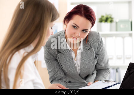 Due femmina conti guardando alla relazione finanziaria analizzando le tabelle ed i grafici. Internal Revenue Service verifica impostazioni documento finanziario. Pianificazione Foto Stock