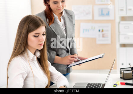 Due femmina conti guardando alla relazione finanziaria analizzando le tabelle ed i grafici. Internal Revenue Service verifica impostazioni documento finanziario. Pianificazione Foto Stock