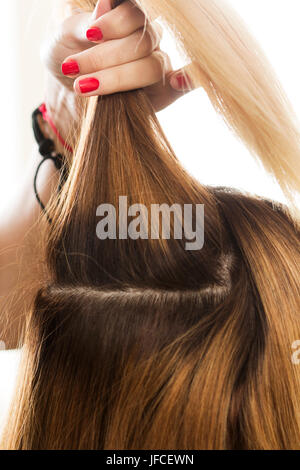 Vista ravvicinata del parrucchiere mano azienda ciocca di capelli la preparazione per il taglio e la tintura dei capelli. Cura dei capelli -, la creazione di un nuovo taglio di capelli, cheratina e restauro ha Foto Stock