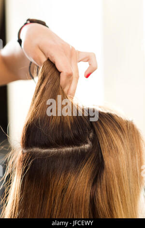 Vista ravvicinata del parrucchiere mano azienda ciocca di capelli la preparazione per il taglio e la tintura dei capelli. Cura dei capelli -, la creazione di un nuovo taglio di capelli, cheratina e restauro ha Foto Stock