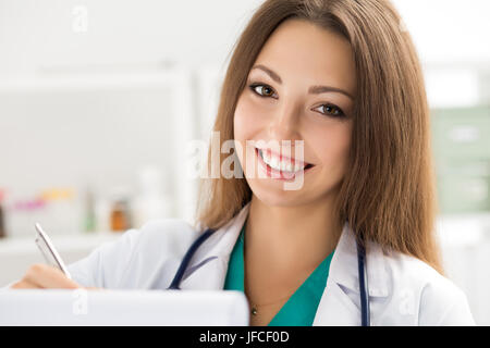 Ritratto di donna sorridente medico al lavoro. Riempimento della donna nel paziente la storia medica elenco. Assistenza sanitaria, cure mediche, assicurazione, prescrizione, s Foto Stock