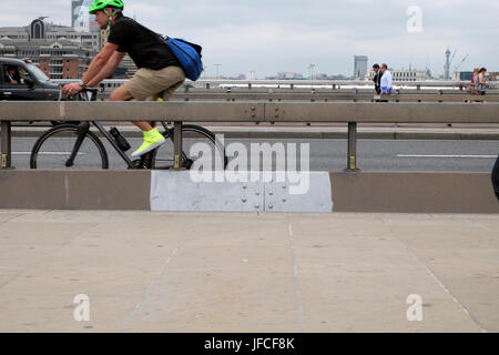 Ciclista di " commuters " Ciclismo su London Bridge accanto a anti-terrorismo di barriera in cemento dopo l attacco di coltello a Borough Market 3 giugno 2017 UK KATHY DEWITT Foto Stock