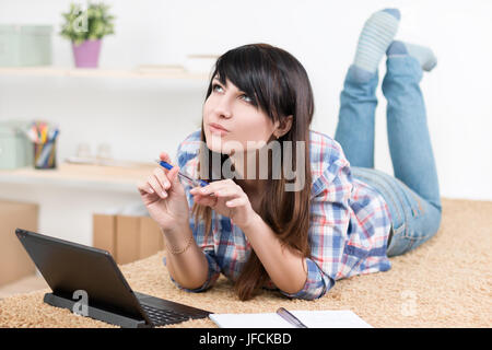 Ragazza adolescente lo studio a casa sdraiato sul divano Foto Stock