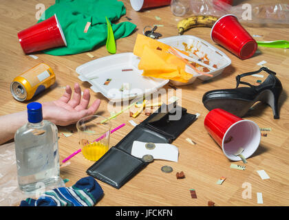 L uomo ha passato fuori sul pavimento dopo partying selvaggi, mano visibile. Terribile sbornia e disordine nell'appartamento. Cestino, gli avanzi di cibo, vestiti, tacchi alti Foto Stock