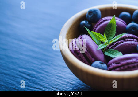 Amaretti rosa con mirtilli su sfondo nero Foto Stock