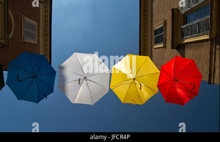 Gli ombrelli di diversi colori su strada con il blu del cielo come sfondo Foto Stock