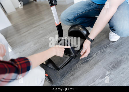 Può spiegarci questo. Su scala di colpo di una femmina shopper puntando il dito in corrispondenza di un bilanciamento auto scooter chiedendo uno store manager di circa il Foto Stock