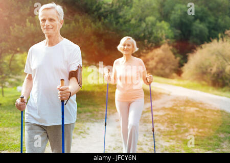 Attività sportiva. Bello felice Nizza uomo azienda walking e praticare il Nordic walking pur essendo all'aperto Foto Stock