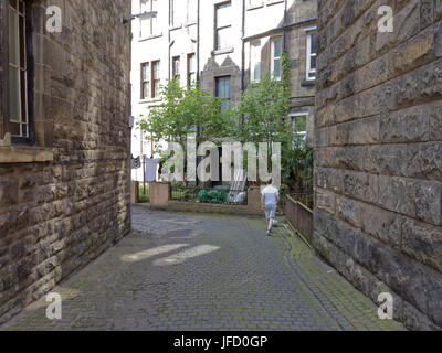 Glasgow vita tenements sfondo arenaria bionda indietro corte ragazzo con il calcio Foto Stock