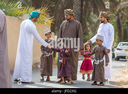 Nizwa, Oman - 26 Giugno 2017: famiglia in abbigliamento tradizionale a un giocattolo sul mercato un giorno di Eid Al Fitr, festa in occasione della fine del mese sacro del Ramadan Foto Stock