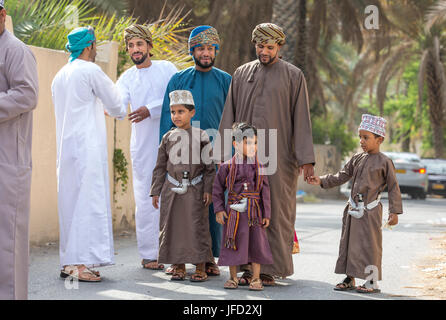 Nizwa, Oman - 26 Giugno 2017: famiglia in abbigliamento tradizionale a un giocattolo sul mercato un giorno di Eid Al Fitr, festa in occasione della fine del mese sacro del Ramadan Foto Stock