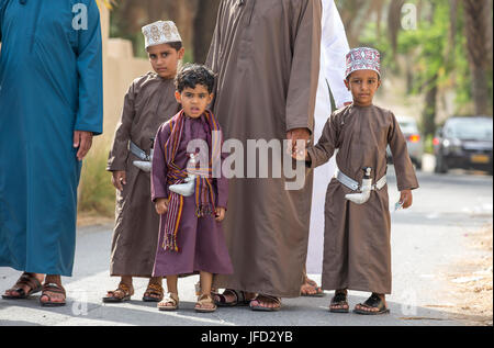 Nizwa, Oman - 26 Giugno 2017: famiglia in abbigliamento tradizionale a un giocattolo sul mercato un giorno di Eid Al Fitr, festa in occasione della fine del mese sacro del Ramadan Foto Stock