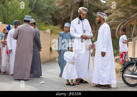 Nizwa, Oman - 26 Giugno 2017: famiglia in abbigliamento tradizionale a un giocattolo sul mercato un giorno di Eid Al Fitr, festa in occasione della fine del mese sacro del Ramadan Foto Stock