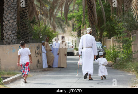 Nizwa, Oman - 26 Giugno 2017: famiglia in abbigliamento tradizionale a un giocattolo sul mercato un giorno di Eid Al Fitr, festa in occasione della fine del mese sacro del Ramadan Foto Stock